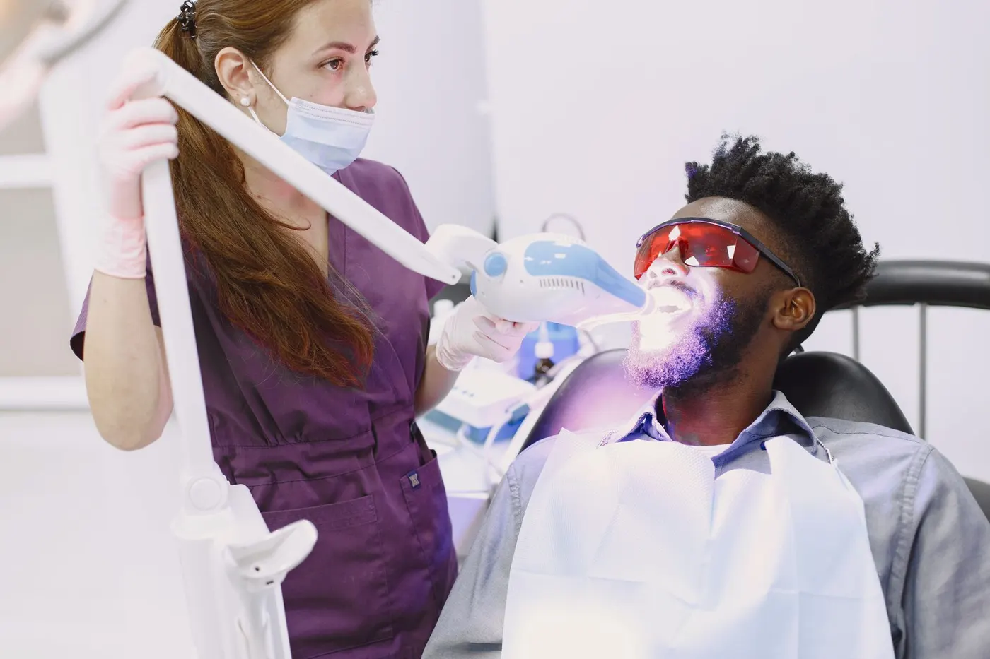 Teeth whitening in the chair — a lamp aimed at the teeth, patient in protective glasses